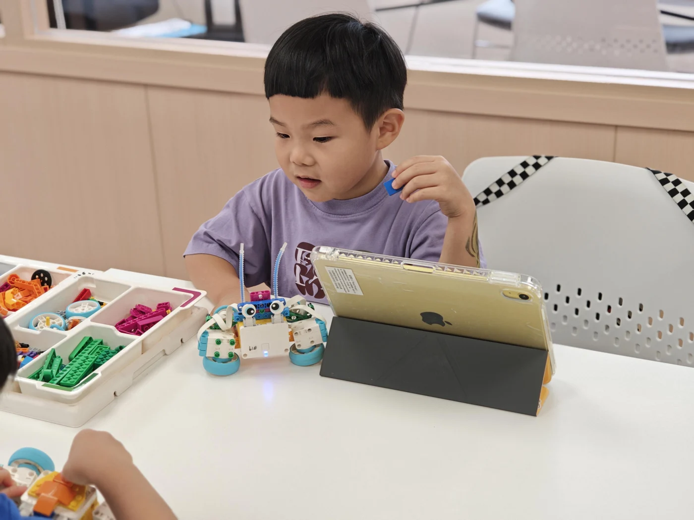 A student exploring a LEGO model beside a tablet