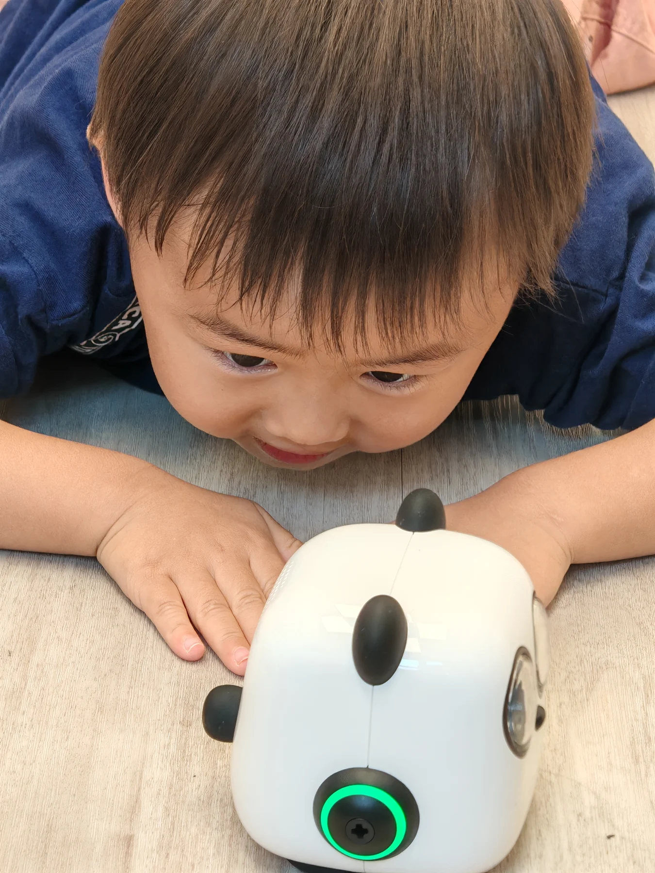 A child closely observing mTiny at floor level