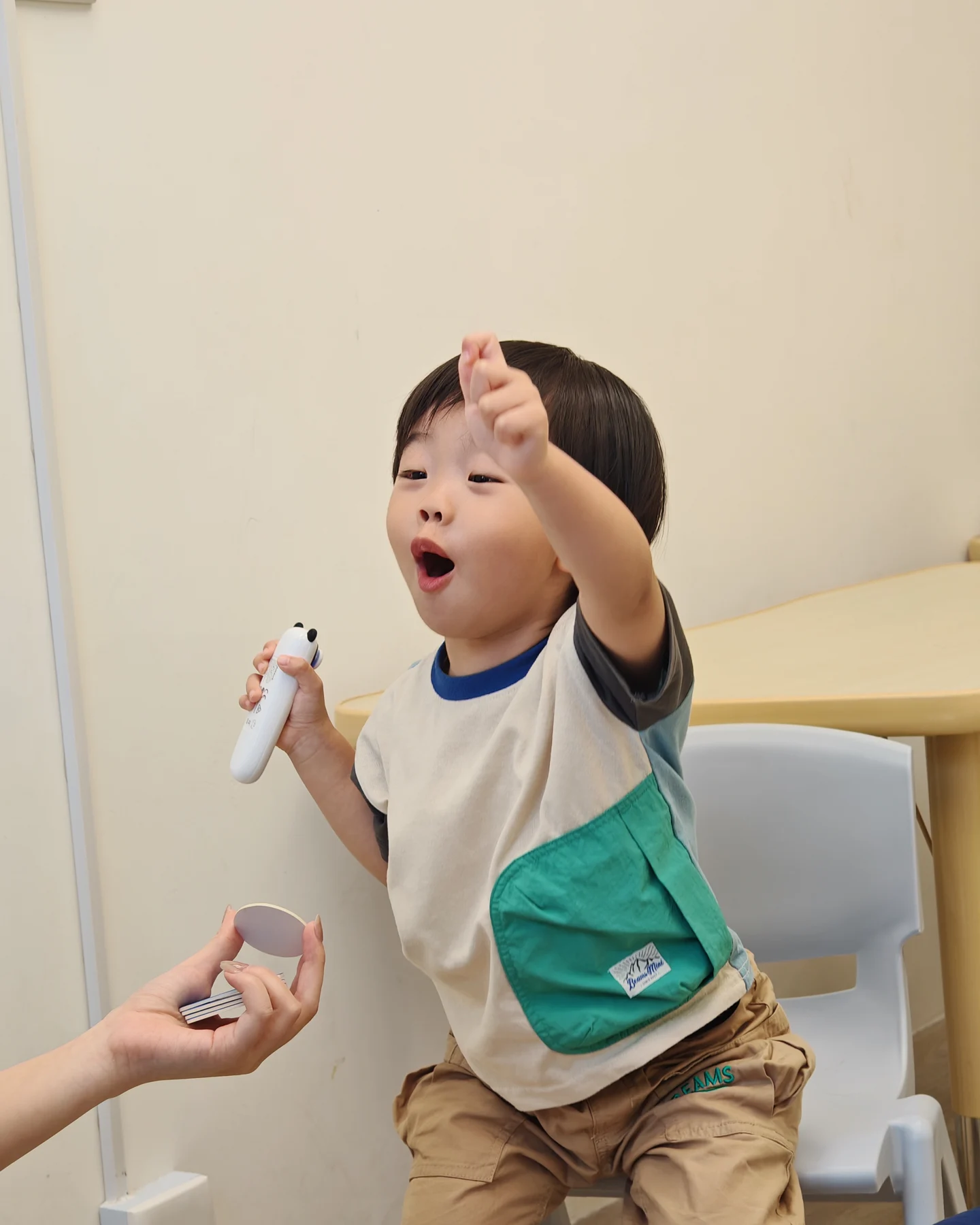 A child raising a hand while holding a controller