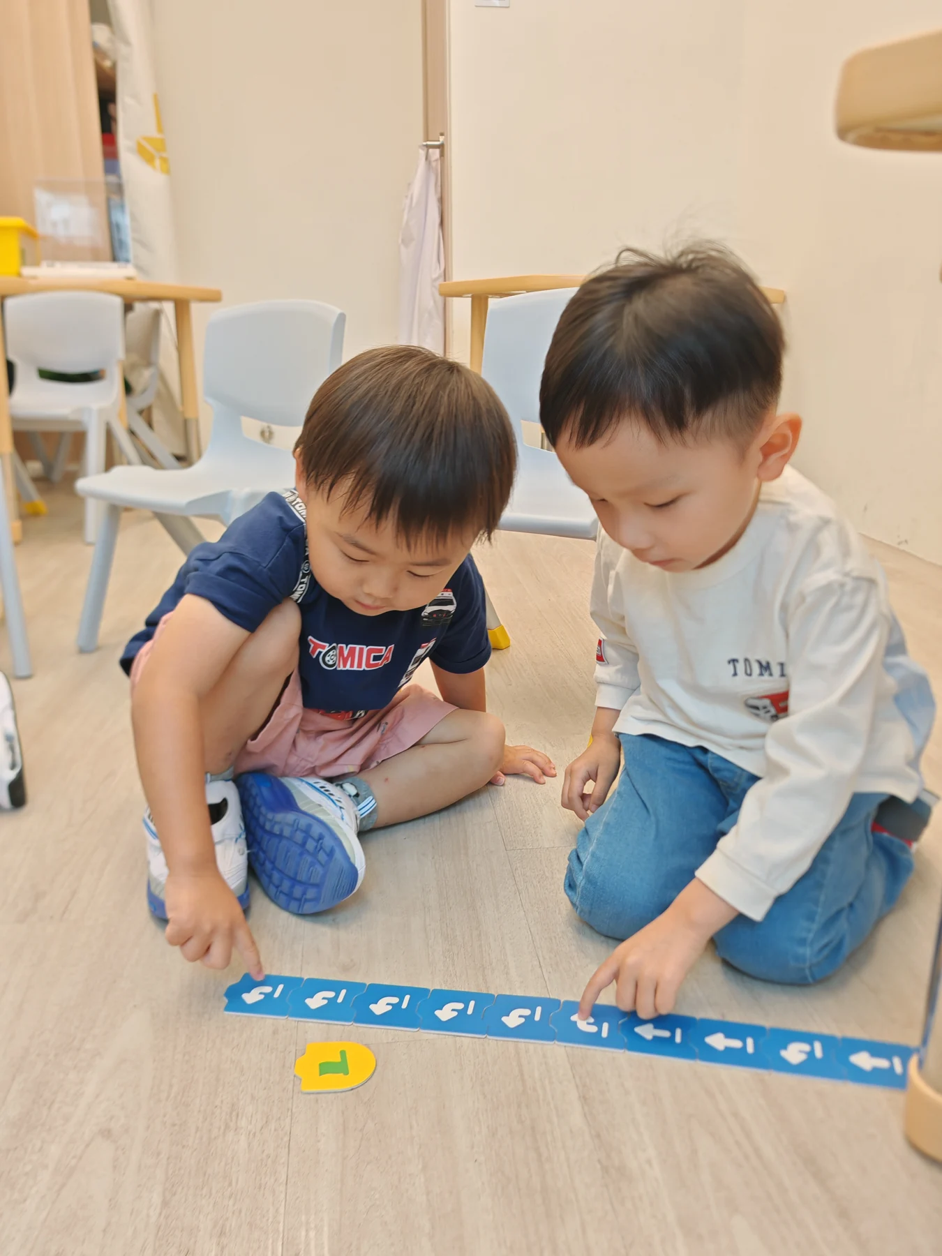 Two children arranging directional coding cards together