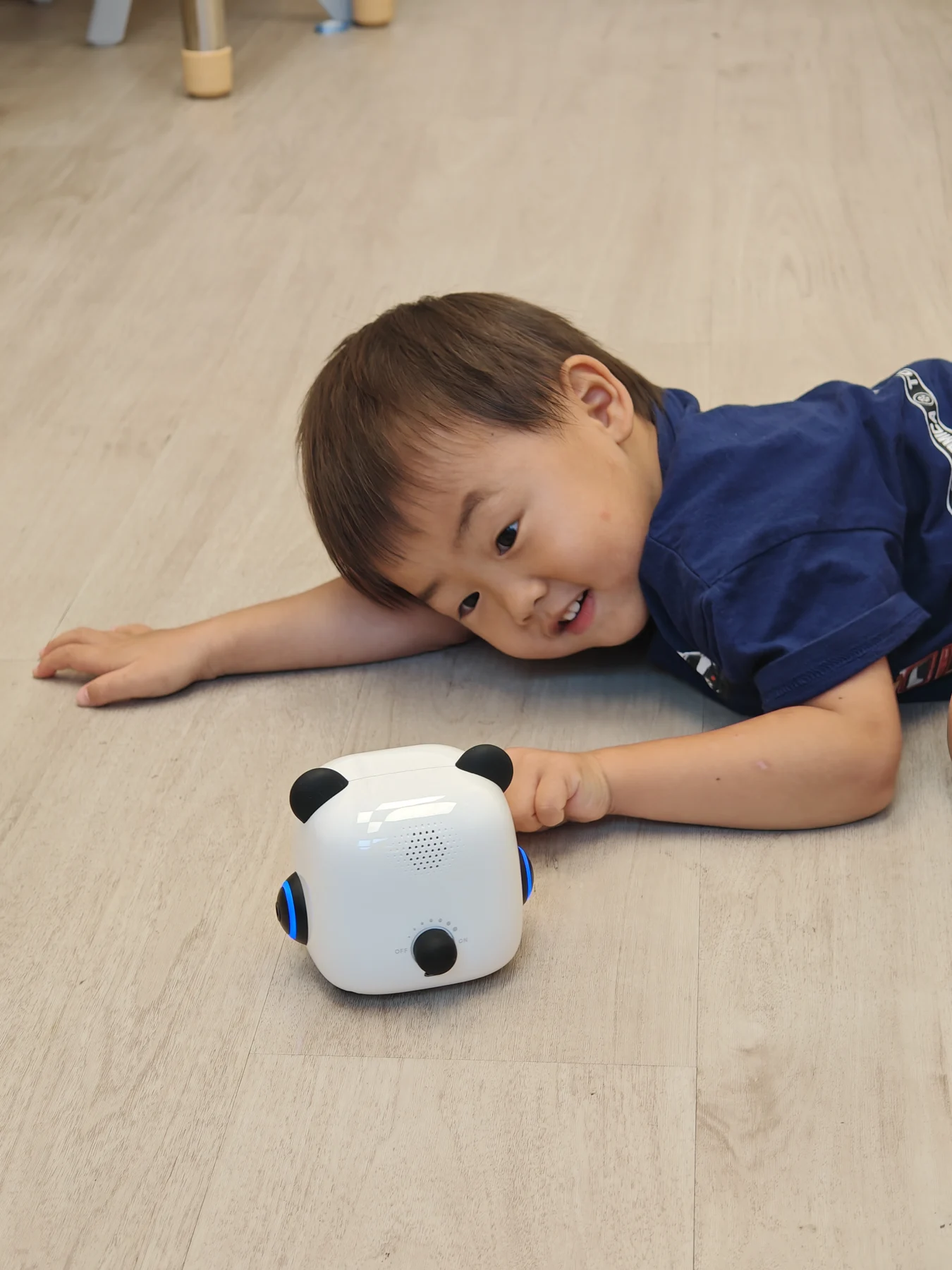 A child looking closely at mTiny on the classroom floor