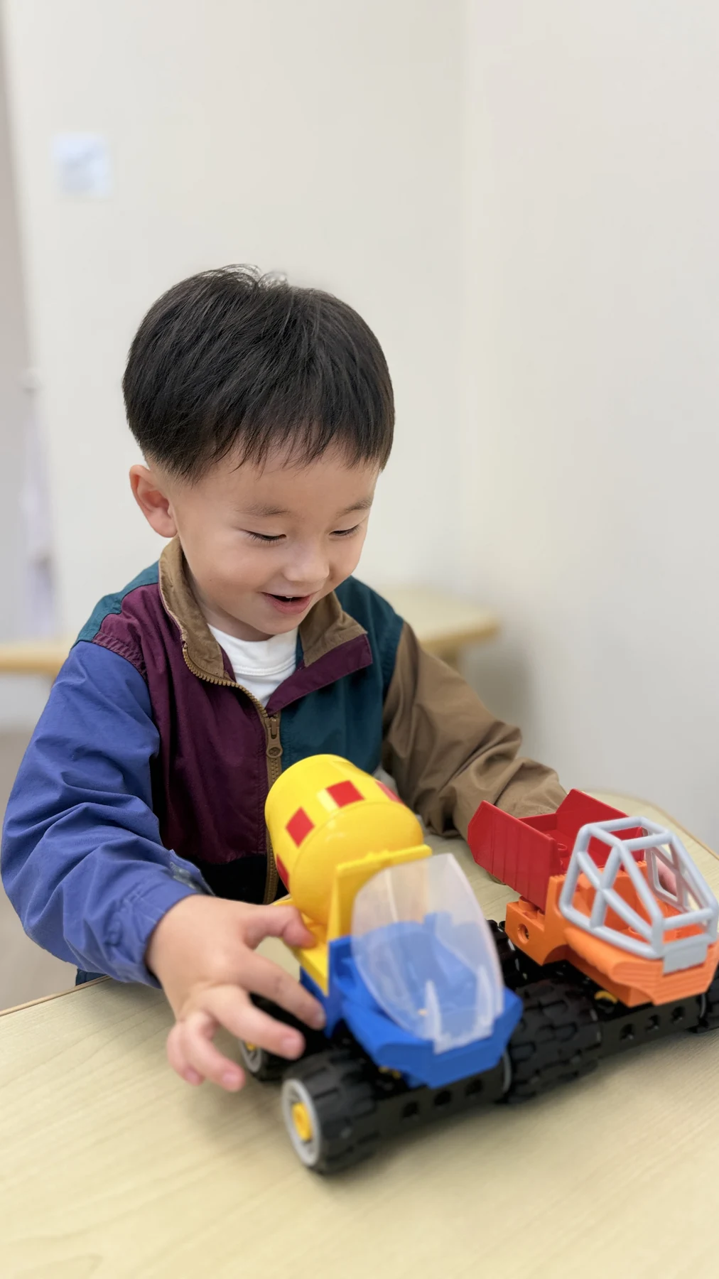 A child exploring large LEGO vehicles at a classroom table