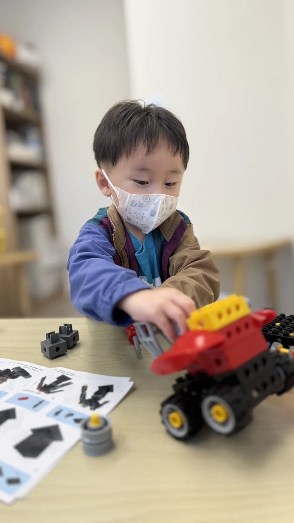 A child exploring a LEGO vehicle with large wheels