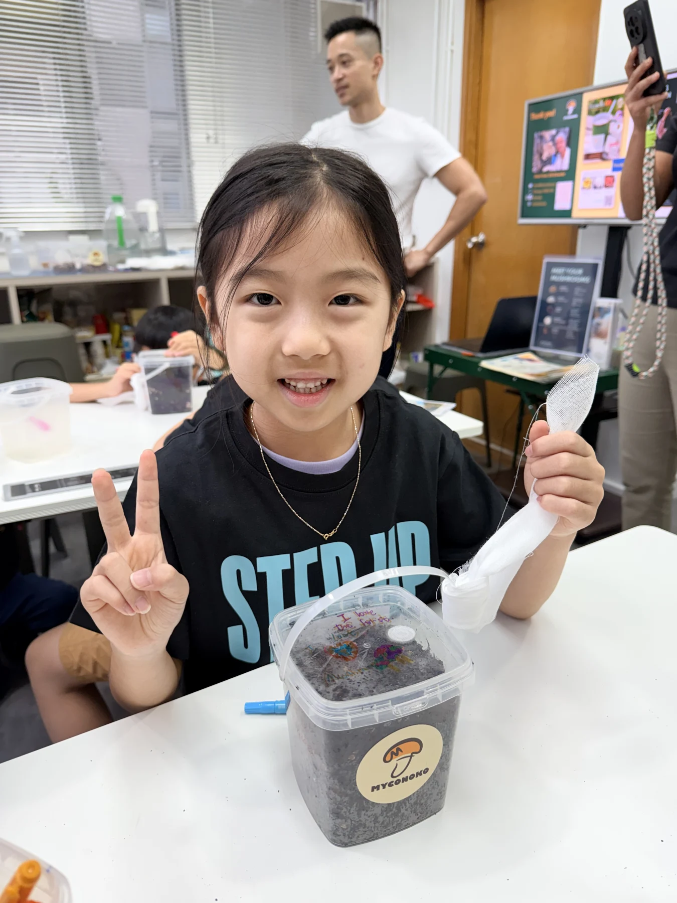 A student showing a take-home mushroom growing kit at Myconoko Lab