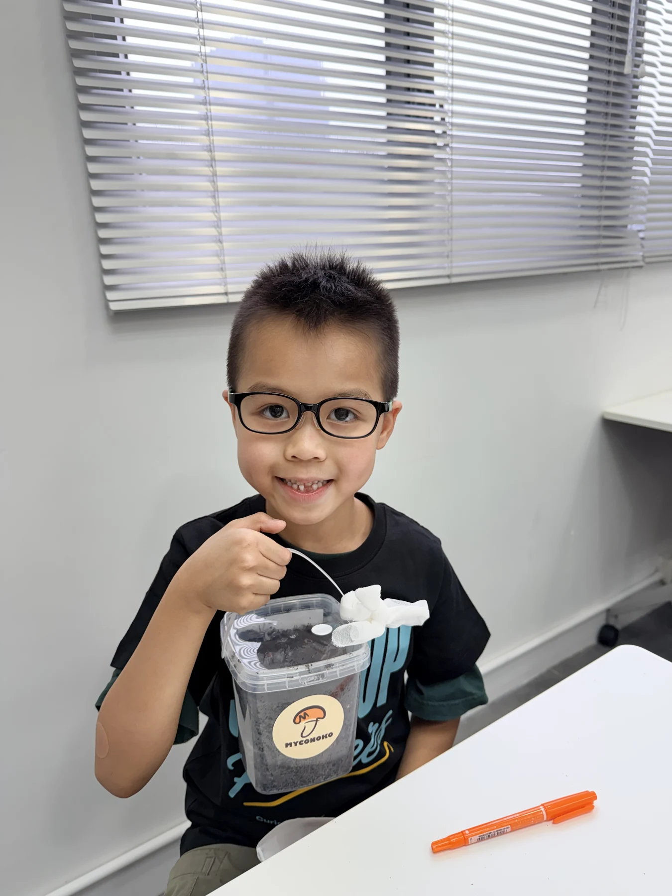 A student showing a take-home mushroom growing kit at Myconoko Lab
