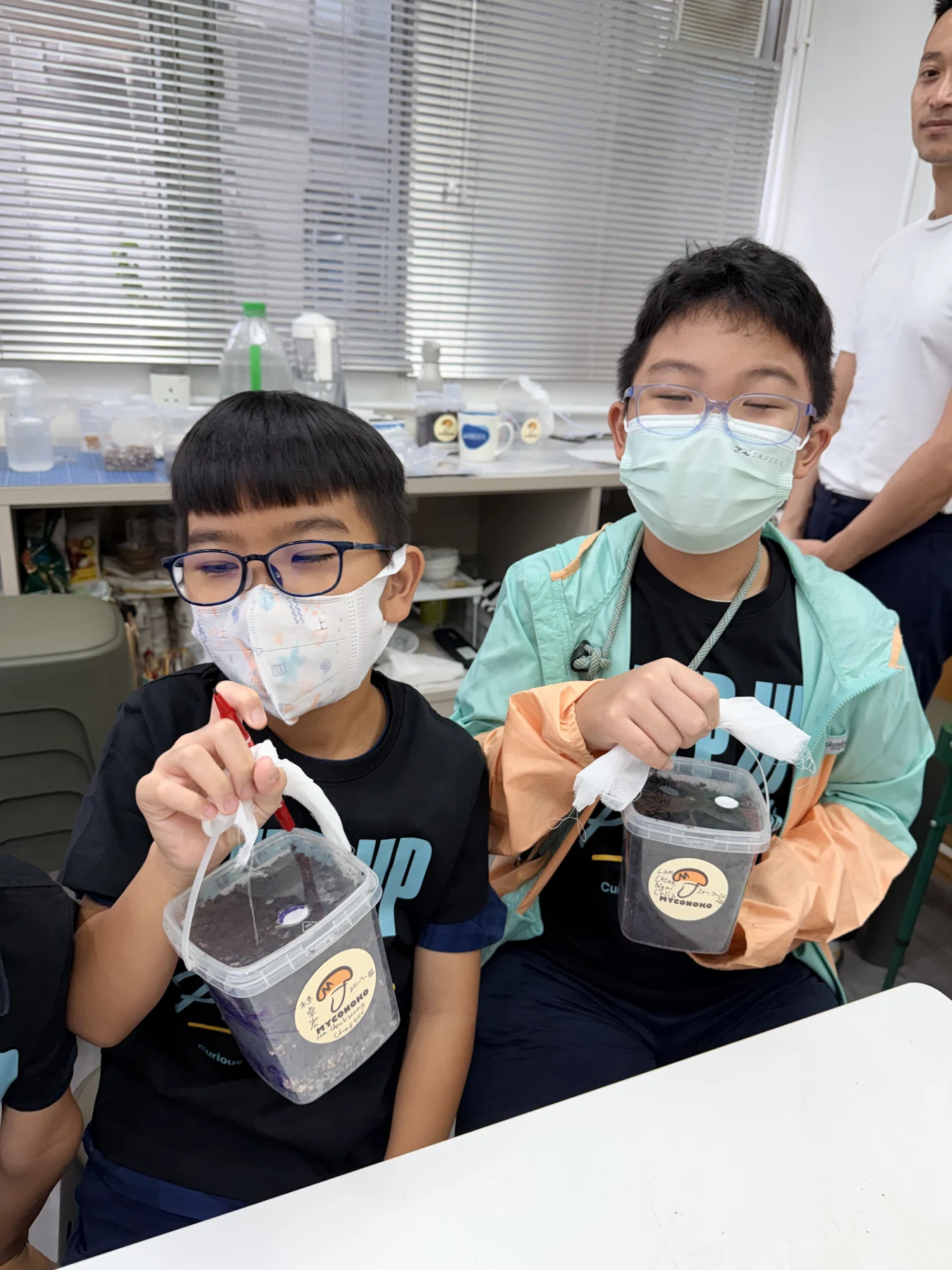 A student showing a take-home mushroom growing kit at Myconoko Lab
