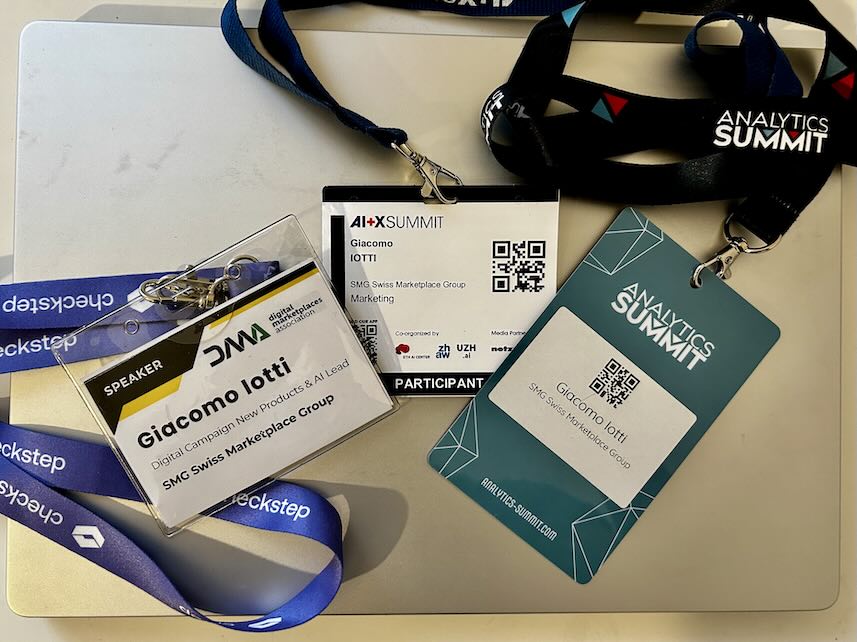 Conference badges for DMA, AI+X Summit, and Analytics Summit on a laptop.