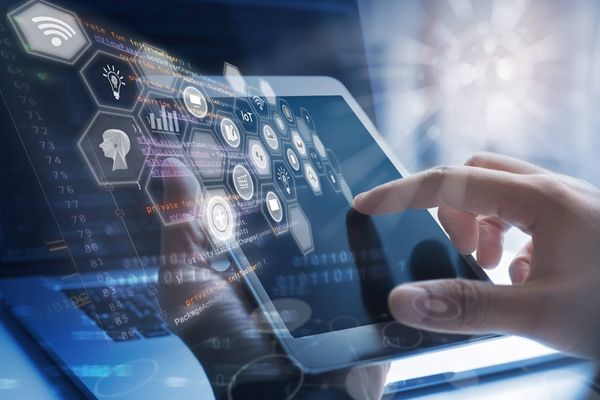 A hand uses a tablet overlaid with connected technology icons, illustrating the networked idea of a digital platform.