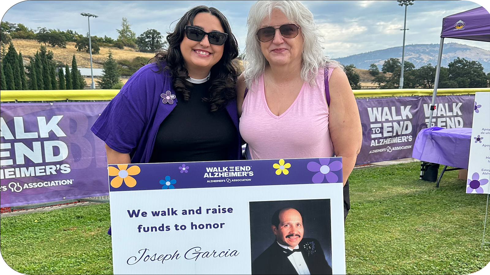 Two women standing by a sign honouring their loved one
