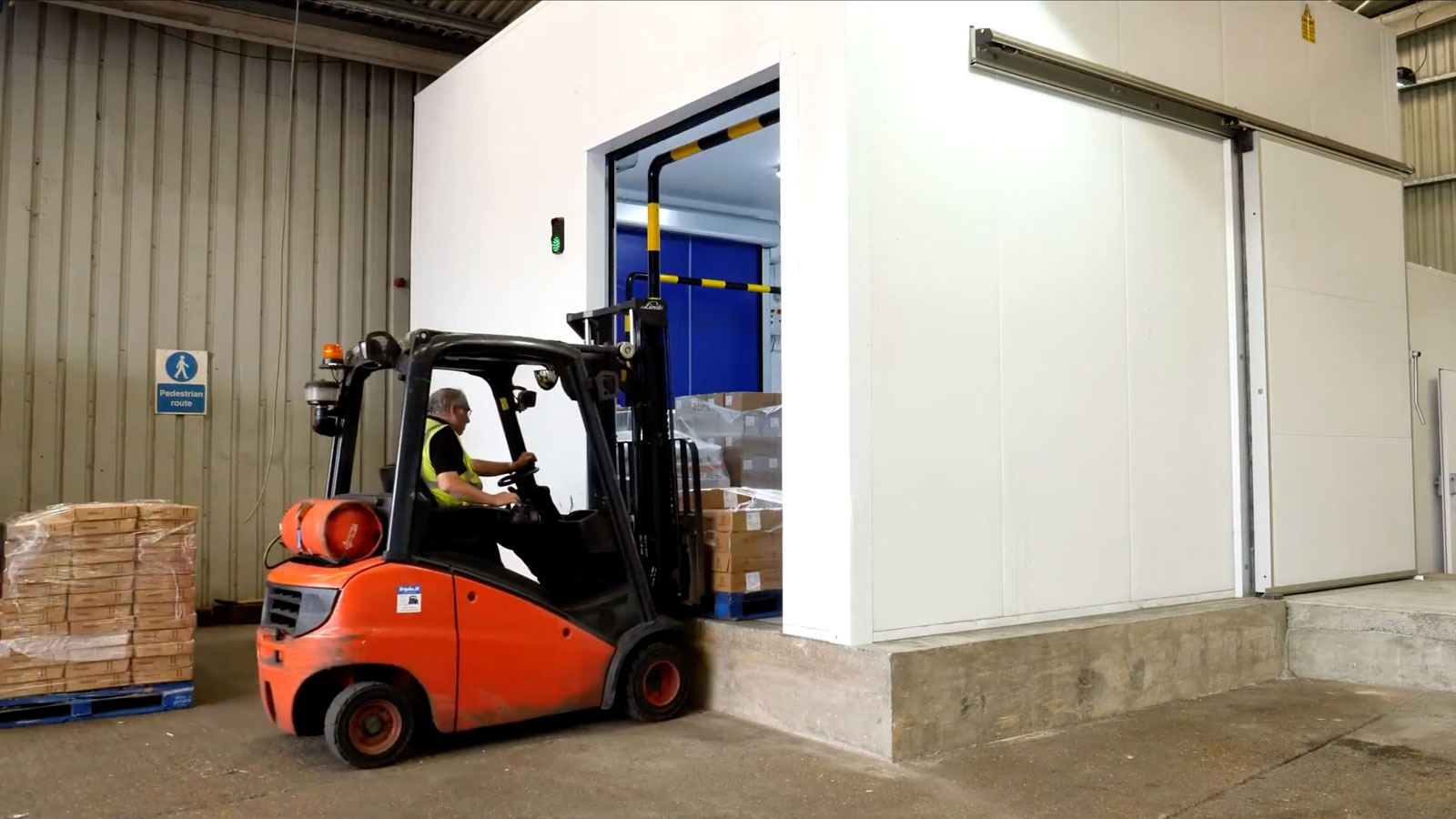 A forklift loading items into a large chiller room