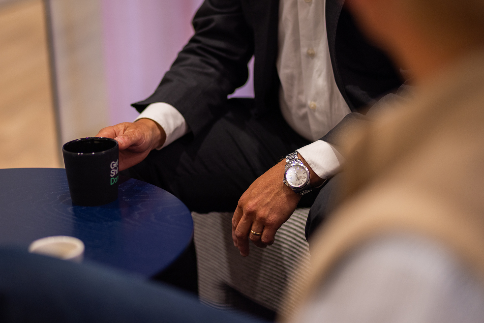 Close-up of Jonas Dahlberg, Head of Growth at Redeploy, reaching for a coffee mug during an interview, with a wristwatch visible on his arm.