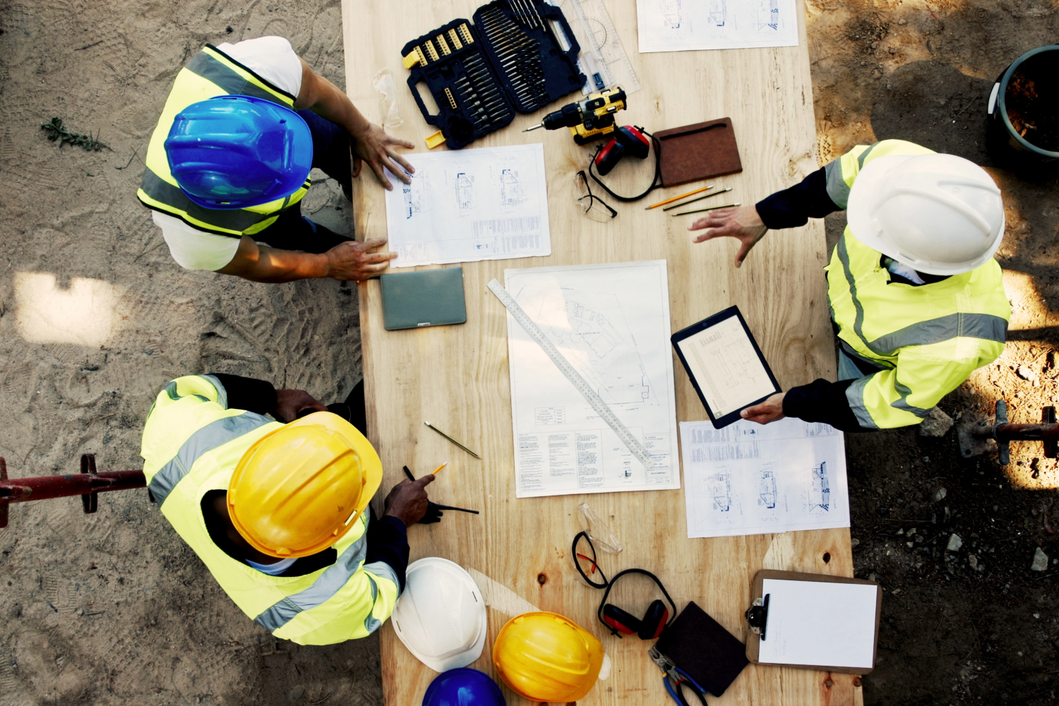 Construction workers discussing project plans and blueprints at a job site.
