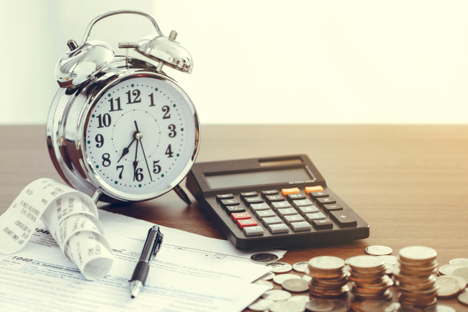 Alarm clock, calculator, coins, and receipts on a desk, symbolizing debt collection strategies.