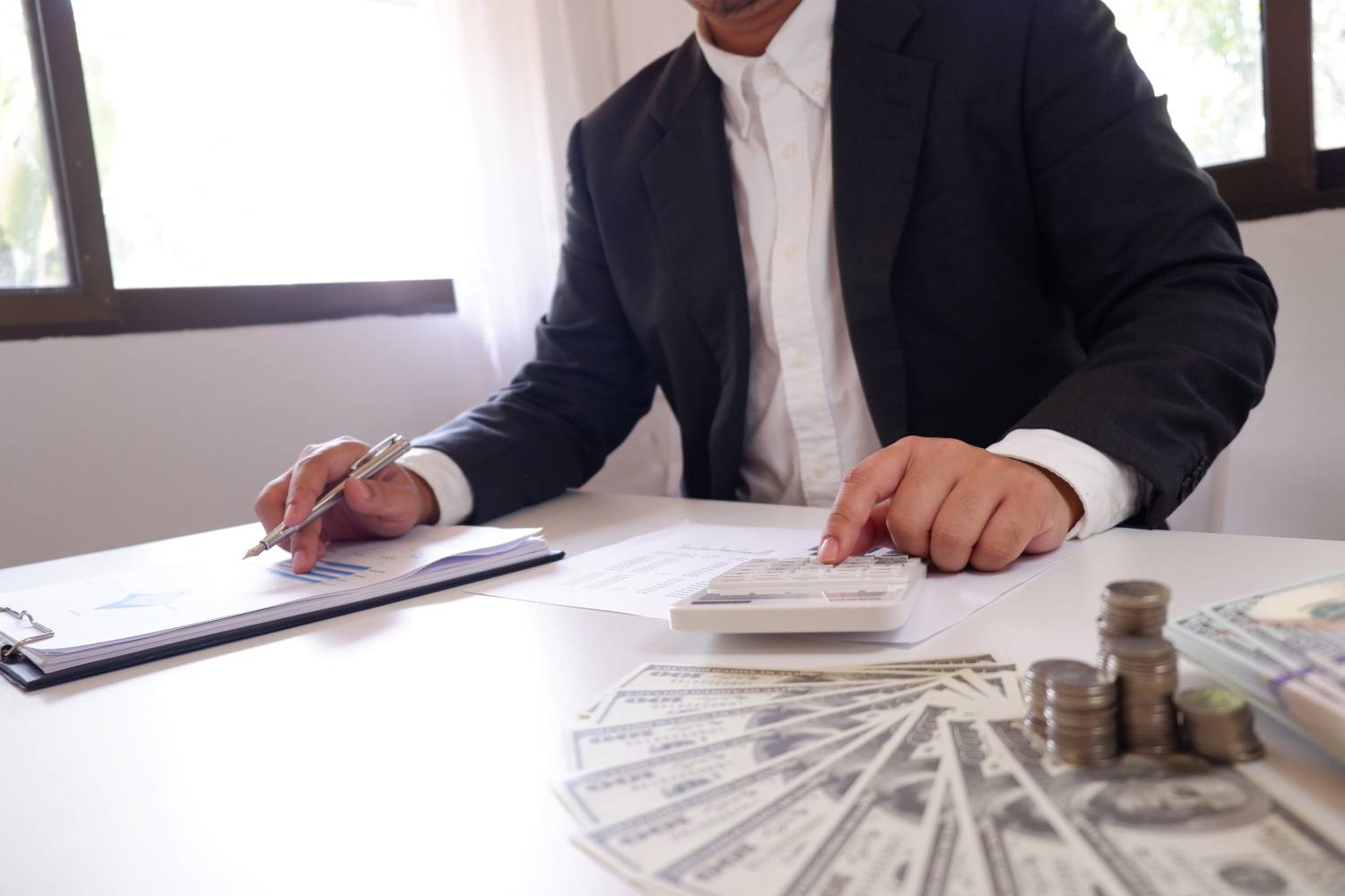 Businessman calculating A/R collection with documents and cash.