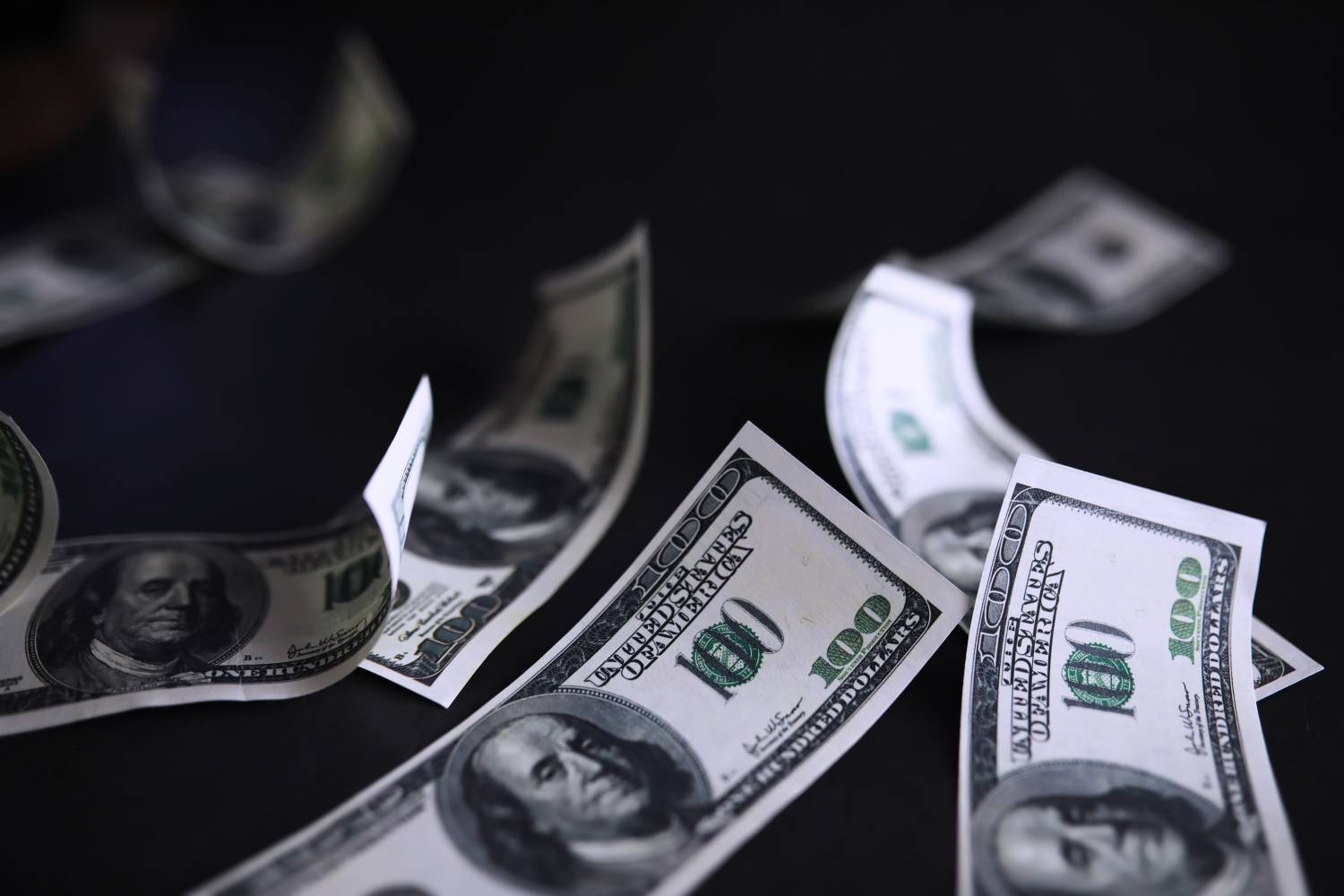 Scattered hundred-dollar bills representing cash flow challenges in commercial debt collection.