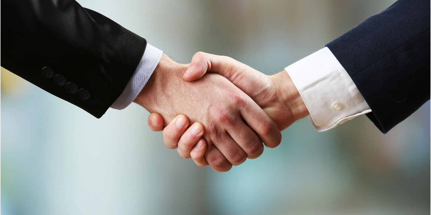 Two businessmen shaking hands, symbolizing agreement in commercial debt collection.