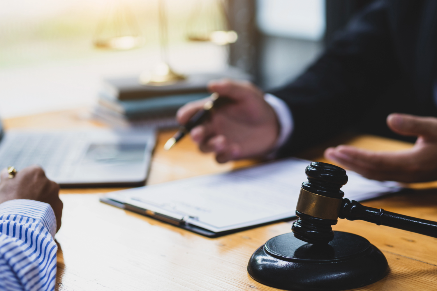 Two people discussing over clipboard and gavel on table.