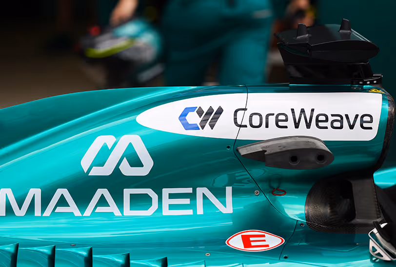 Side view of the Aston Martin Aramco F1 car showing the CoreWeave logo above the MAADEN branding on its teal bodywork