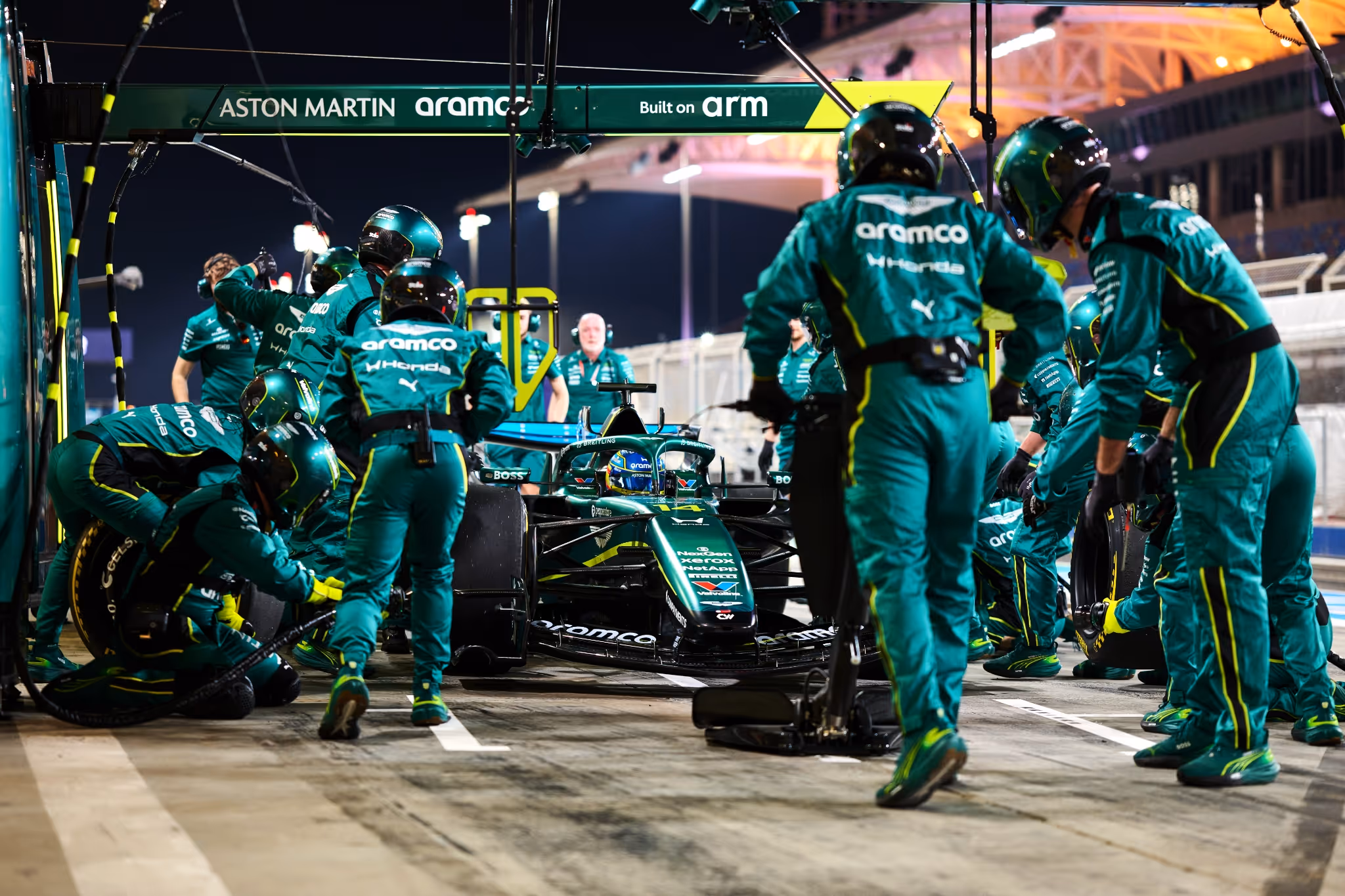 Formula 1 pit crew performing a pit stop on a race car during a night race.