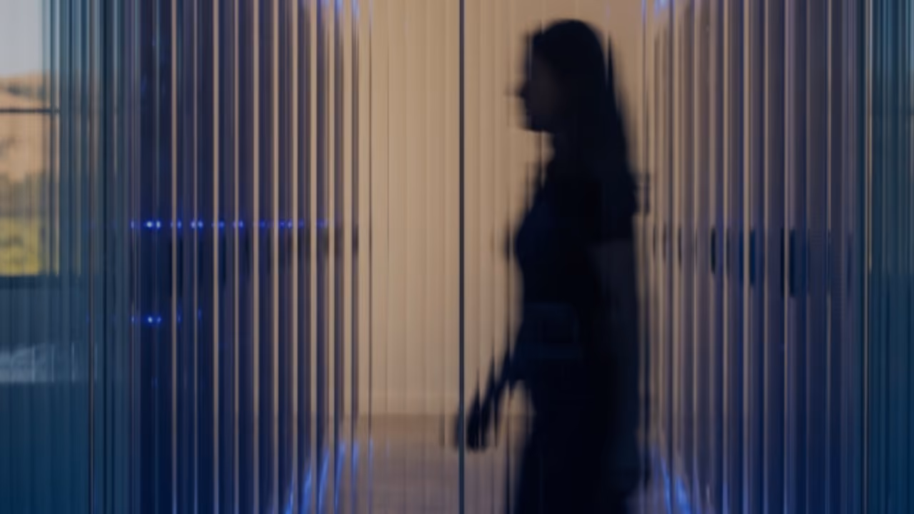 Silhouette of a person walking beside server racks with vertical lines creating a blurred effect.