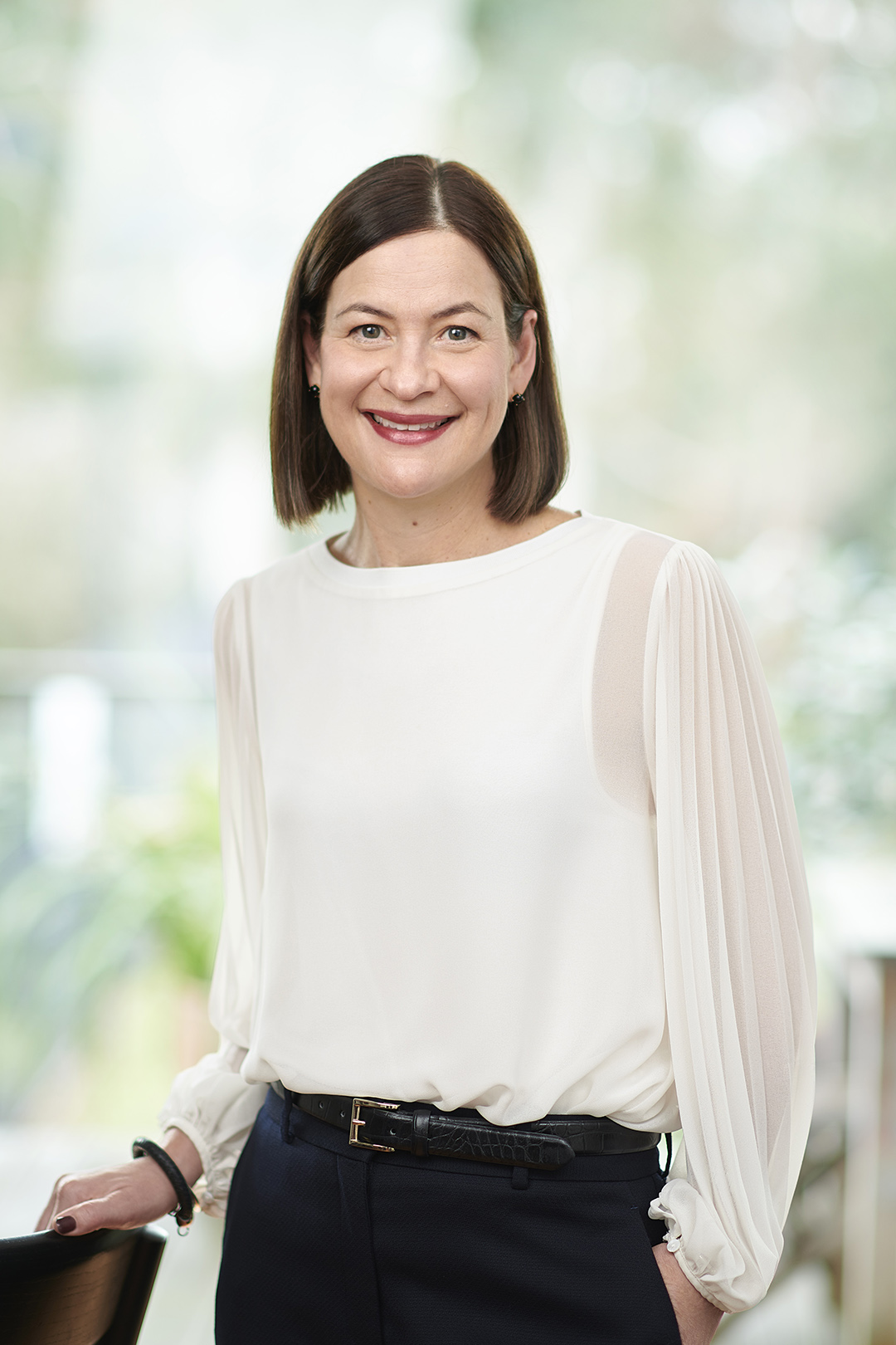 a woman stands smiling with a green background