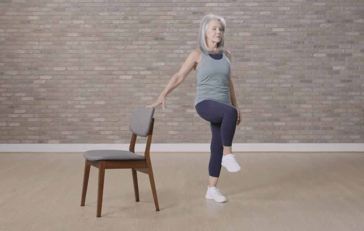 woman using chair for knee raise exercise