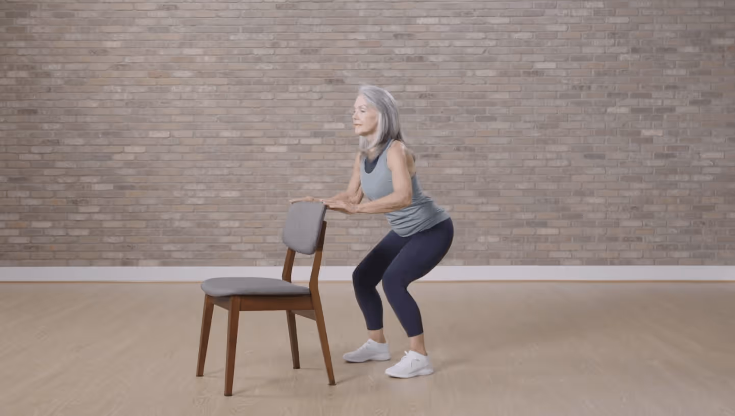 woman doing squat exercise using a chair for support