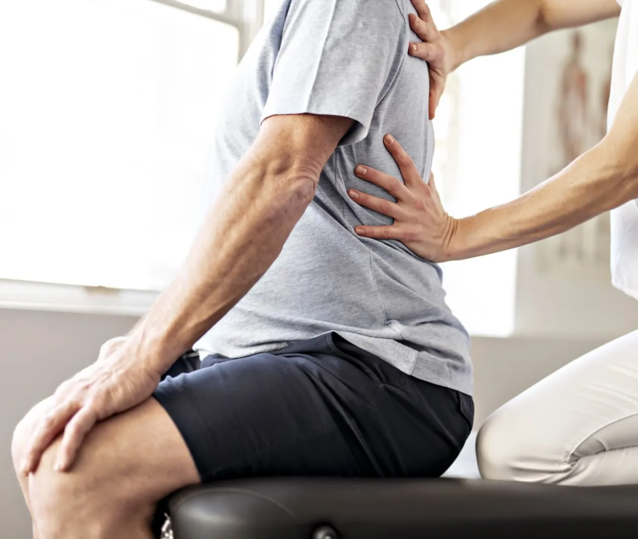 Physical therapist performing manual manipulation to a male patient's back