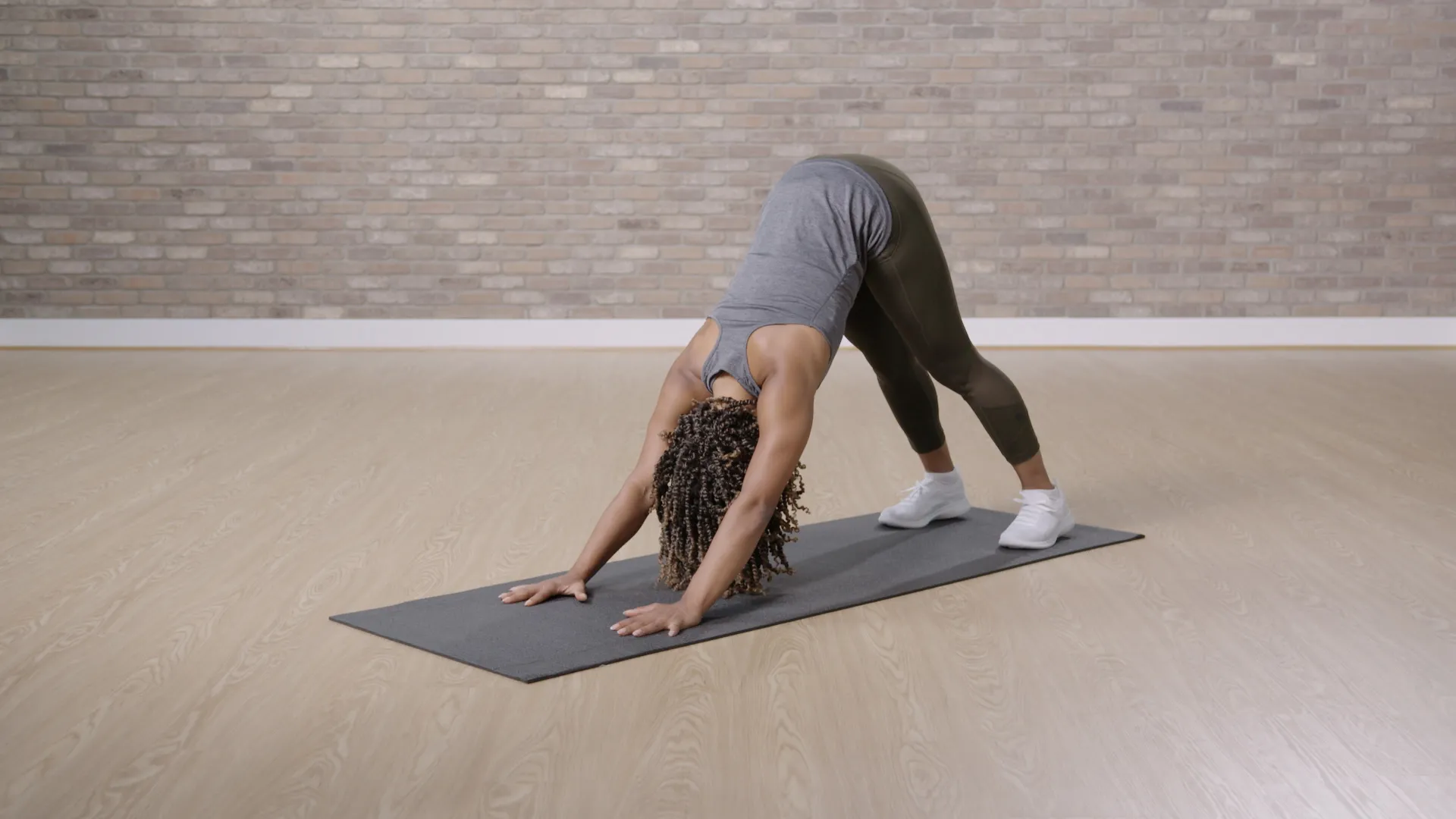 woman doing downward facing dog on a gray yoga mat