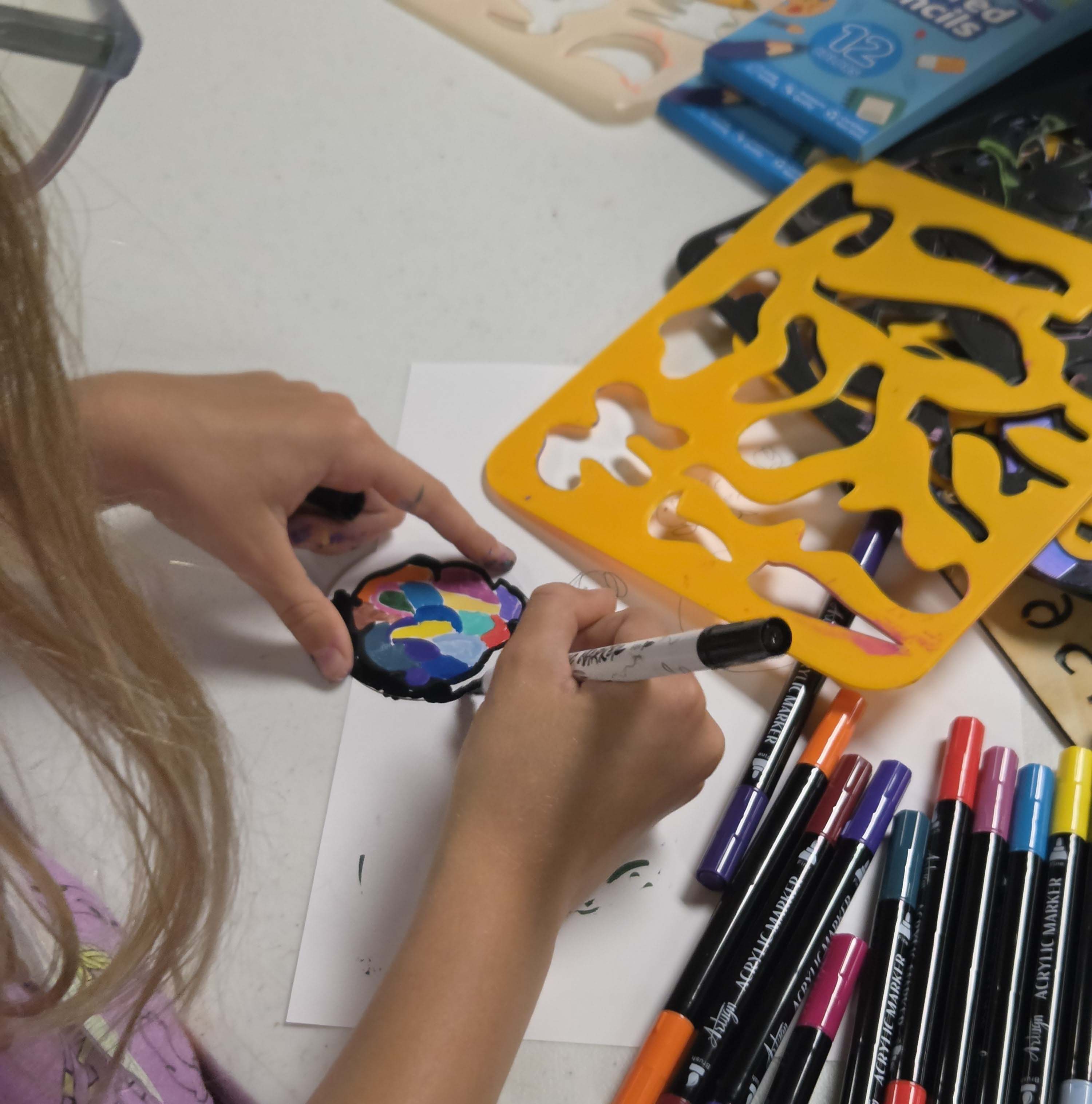 Table with art supplies including paint bottles, paintbrushes, and colored markers on a Make With Sam banner.