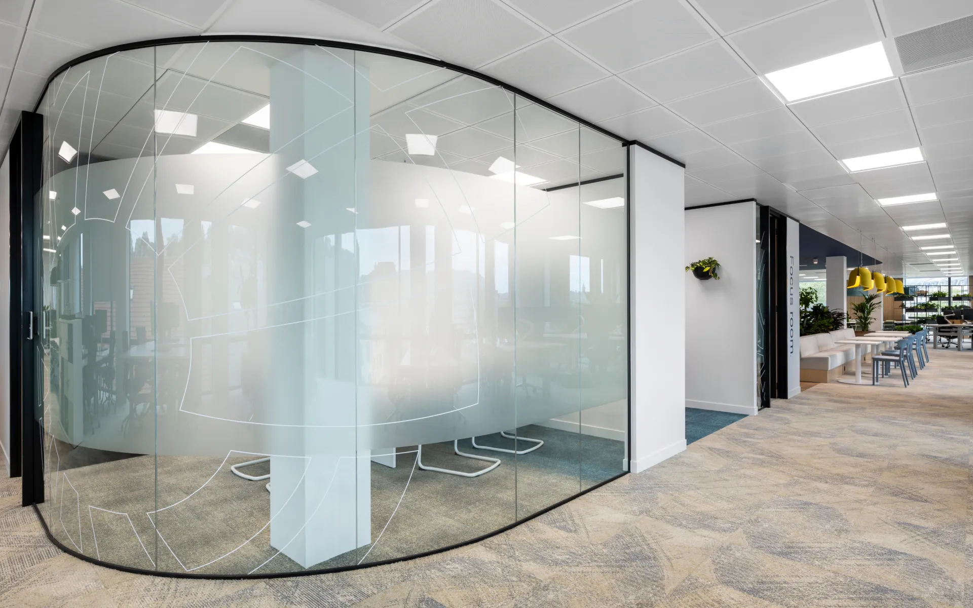 Unique curved glass meeting pod within a minimalist white office interior.