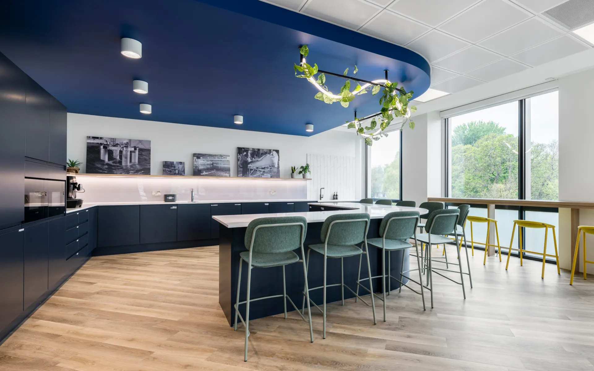 Informal meeting area with high tables, bar stools, and a ceiling mural above.