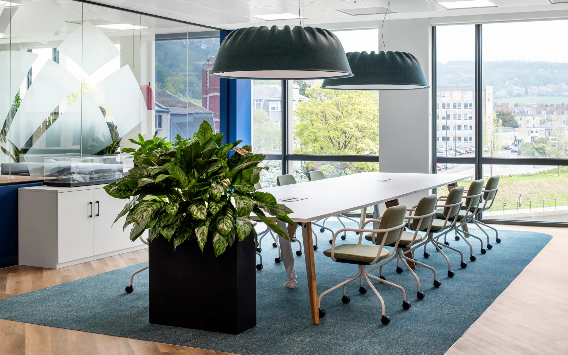The contemporary meeting room with long communal table, pendant lighting, and large windows for natural light.
