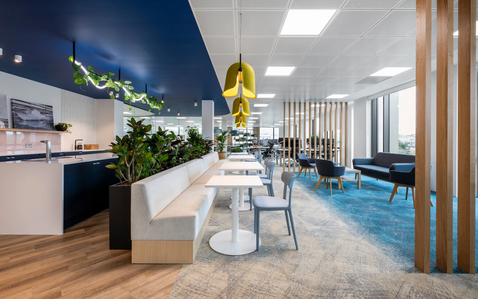 Stylish office corridor with seating areas, planter dividers, and suspended lighting.