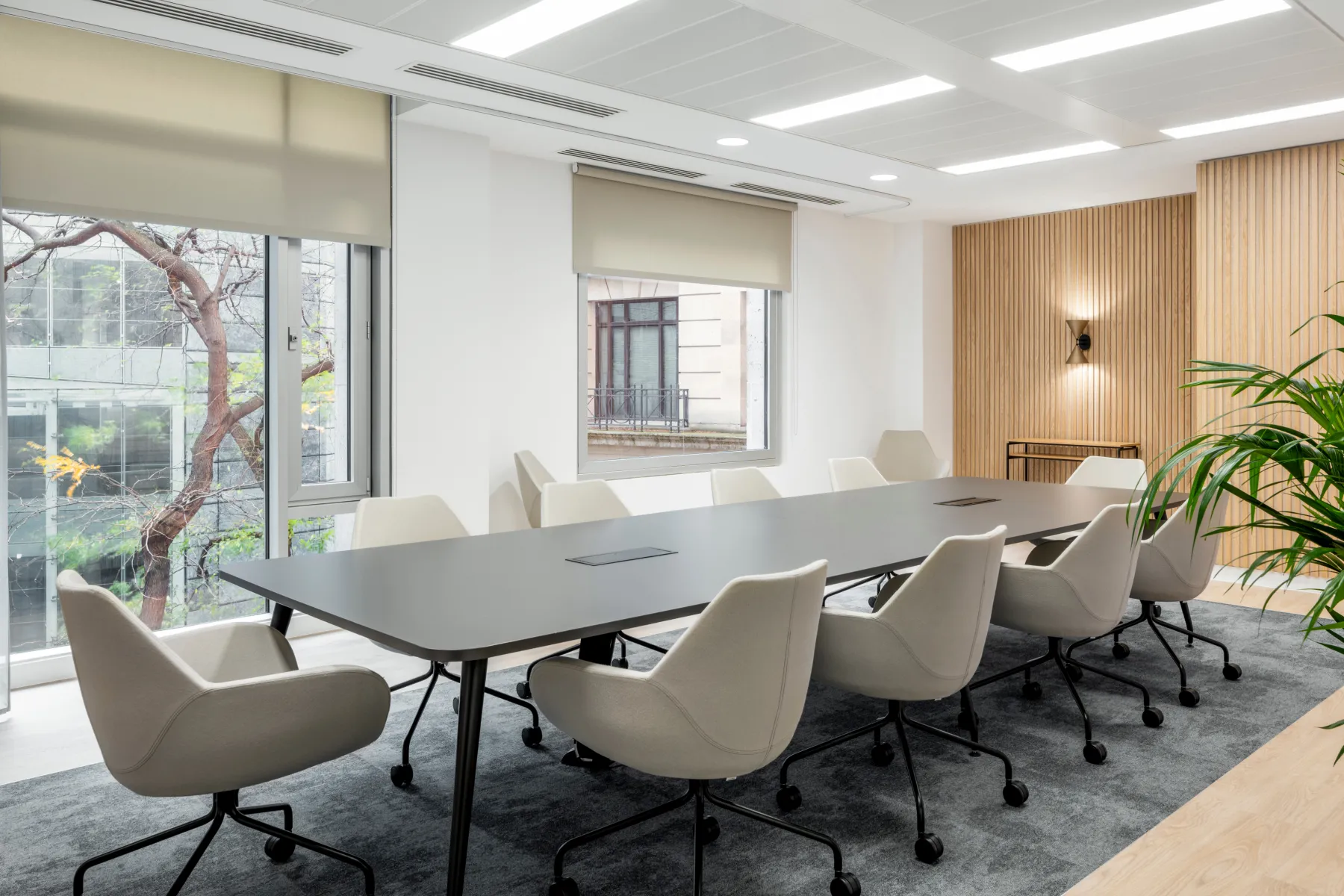 Boardroom with wood panelling a black boardroom table and cream coloured chairs