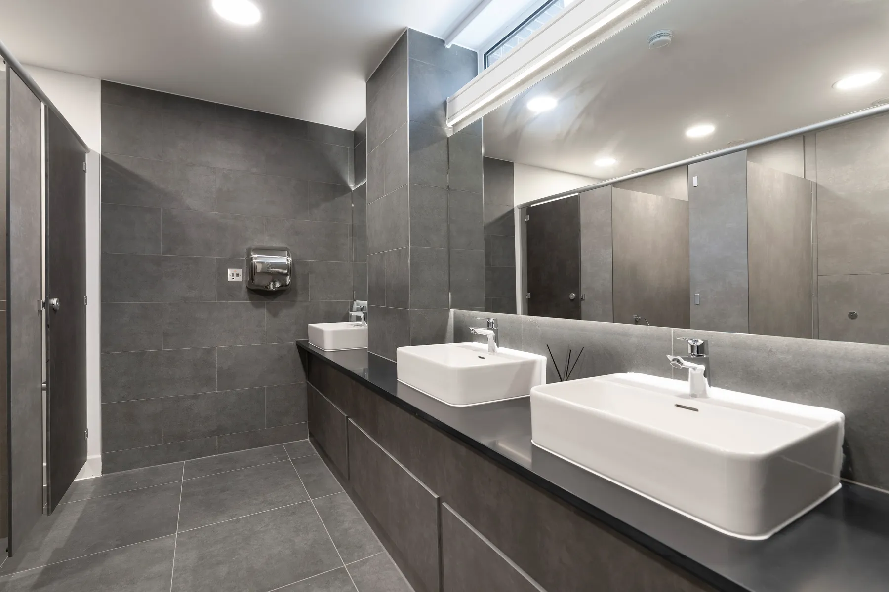 Bathrooms completed to a high standard. With grey tiling and white basins.