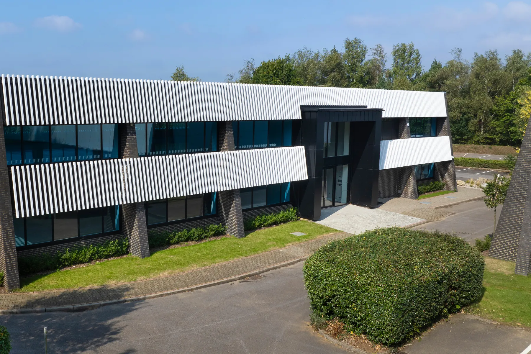 External shot of Inca House. With large full height glass windows and entrance and white cladding.