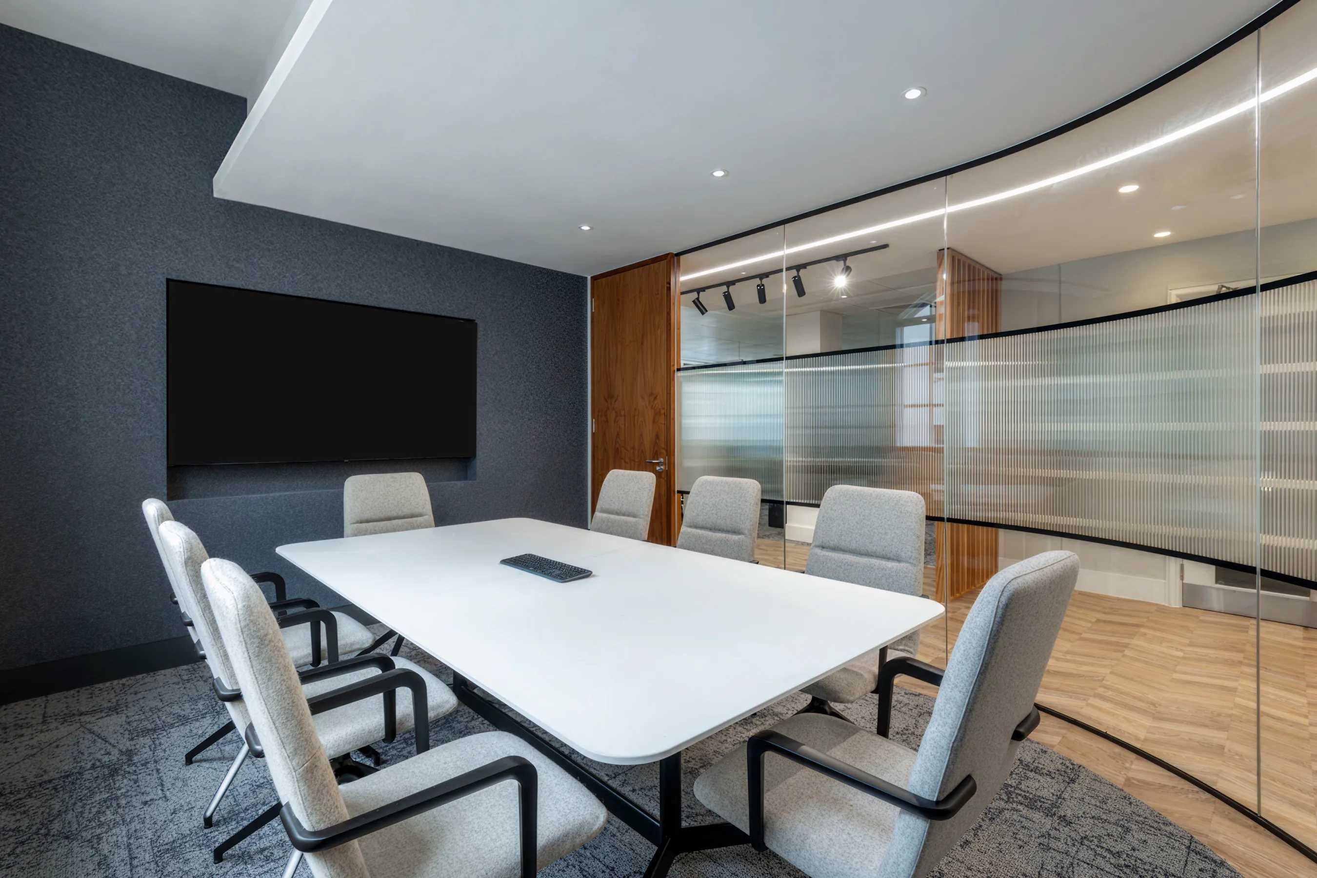 Contemporary conference room with a long white table, modern chairs, and glass walls.