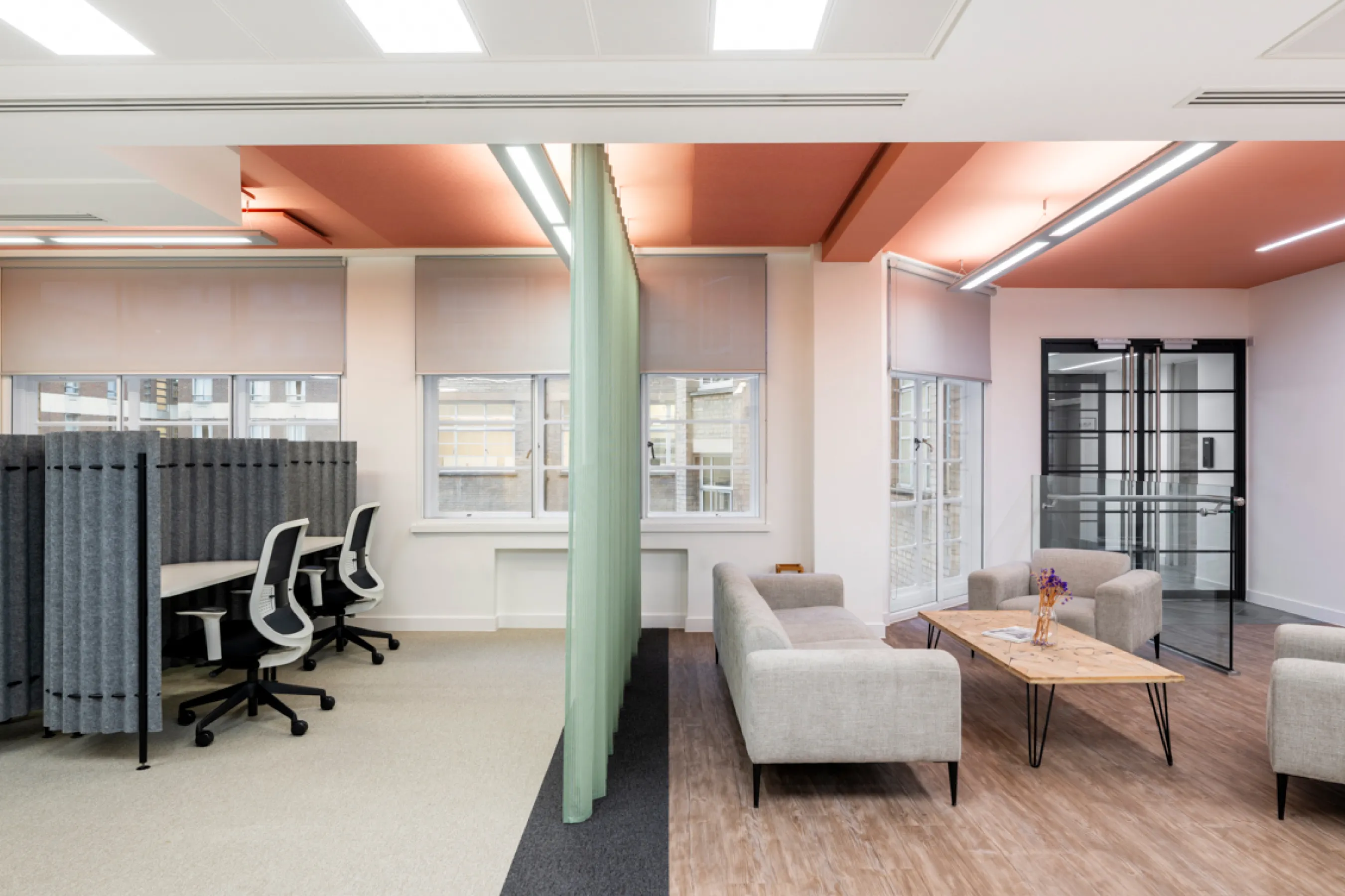 Open office workspace with desks, chairs, exposed ceiling features, and natural light.