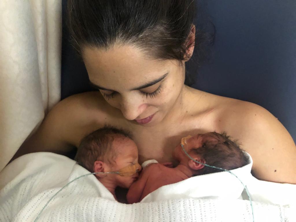 Maria holds her twins to her chest after giving birth.
