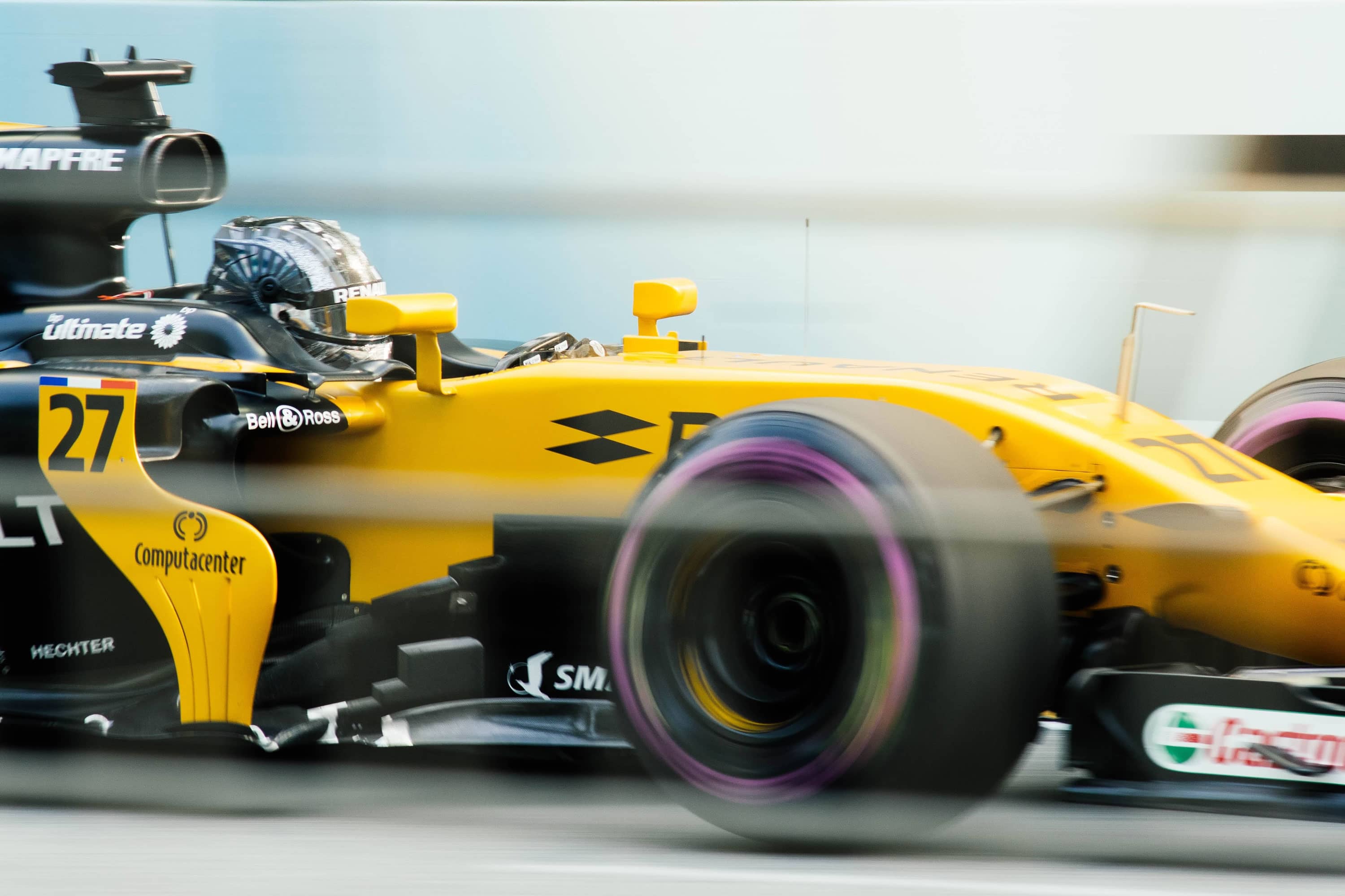 Dynamic photo of formula 1 race car in yellow, with motion blur