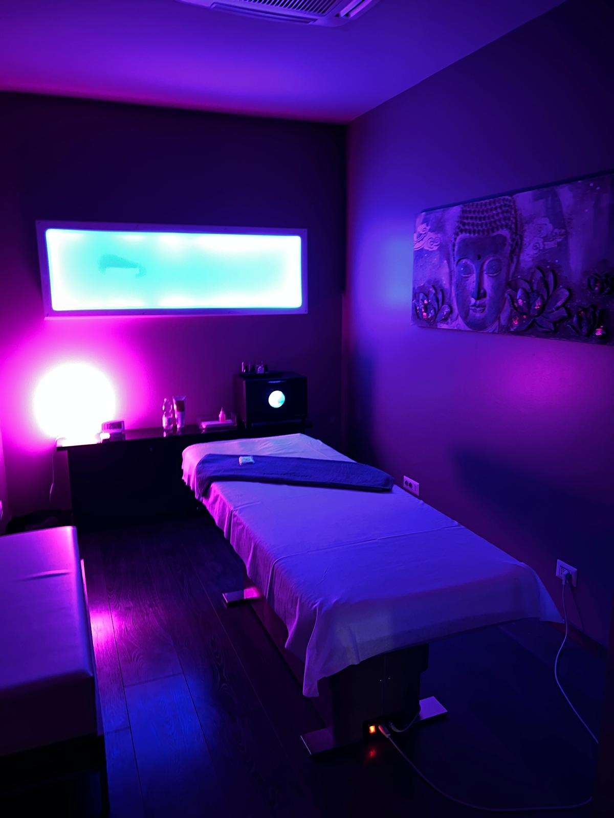Cabina massaggi con luci viola e rosa e quadro del Buddha