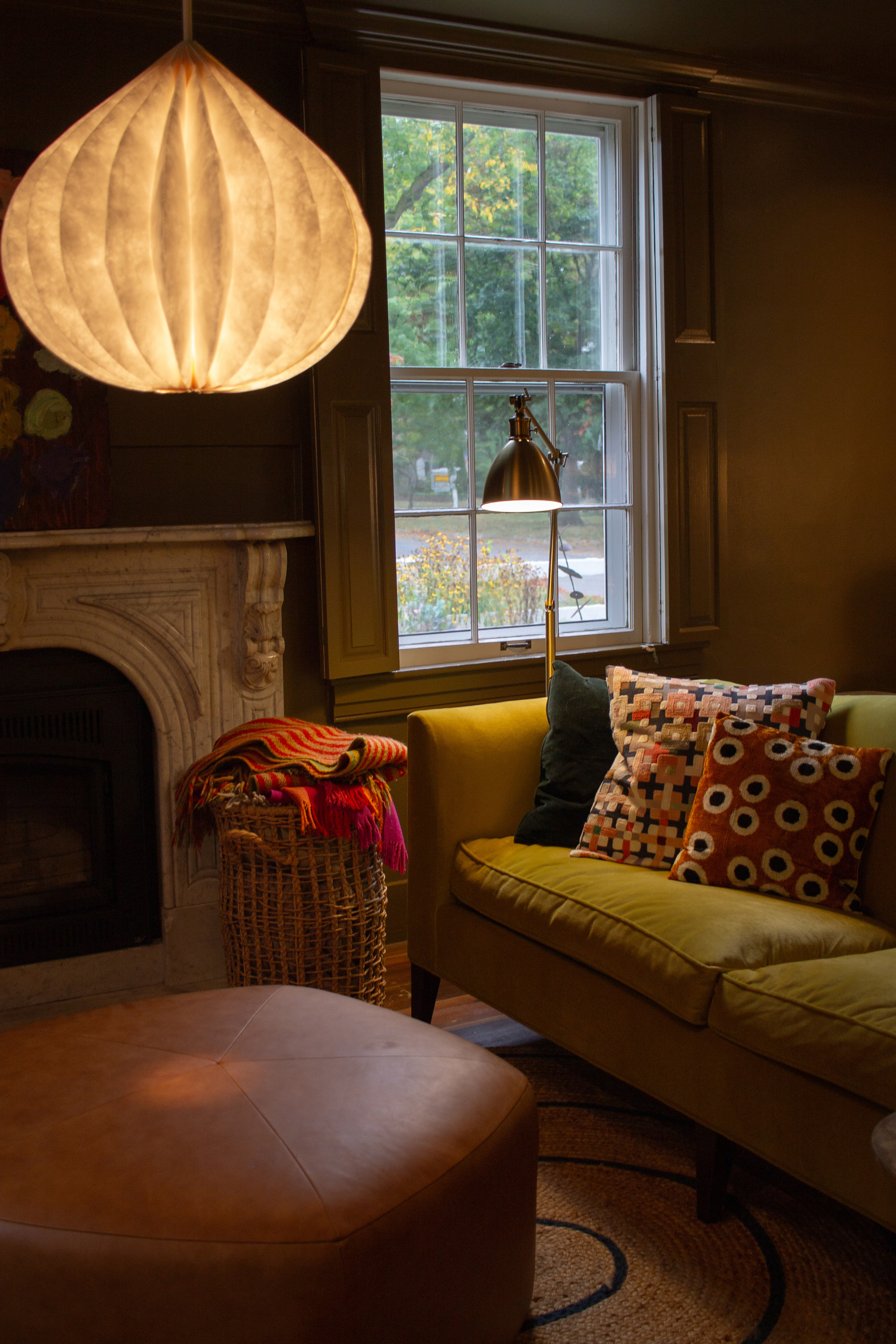 chartreuse green sofa with colorful patterned throw pillows next to a fireplace in a cozy parlor room