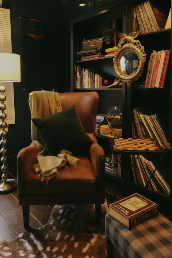 armchair in front of bookshelf adorned with books and knick knacks in the cozy library room at The Federal Inn in Maumee Ohio