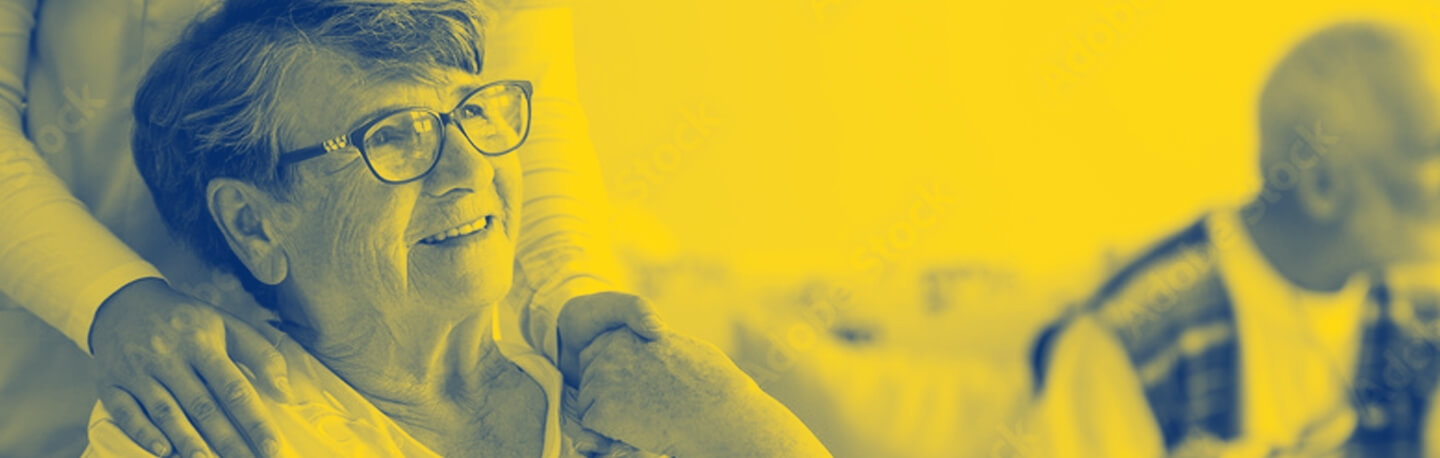 An elderly woman smiling and holding a volunteer's hand.