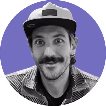 Smiling man with a mustache wearing a cap and a plaid shirt against a purple circular background.