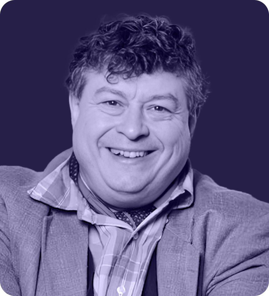 Smiling man with curly hair wearing a striped shirt, scarf, and textured jacket against a dark background.