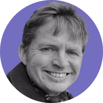 Smiling man with light hair against a purple circular background.