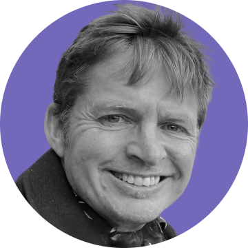 Smiling man with light hair against a purple circular background.