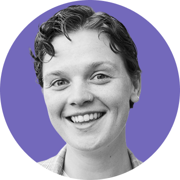 Smiling person with short curly hair and nose ring in front of a purple circular background.